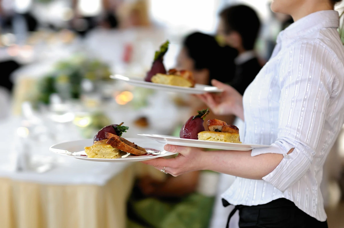 Servicekraft trägt Teller mit essen zum Tisch